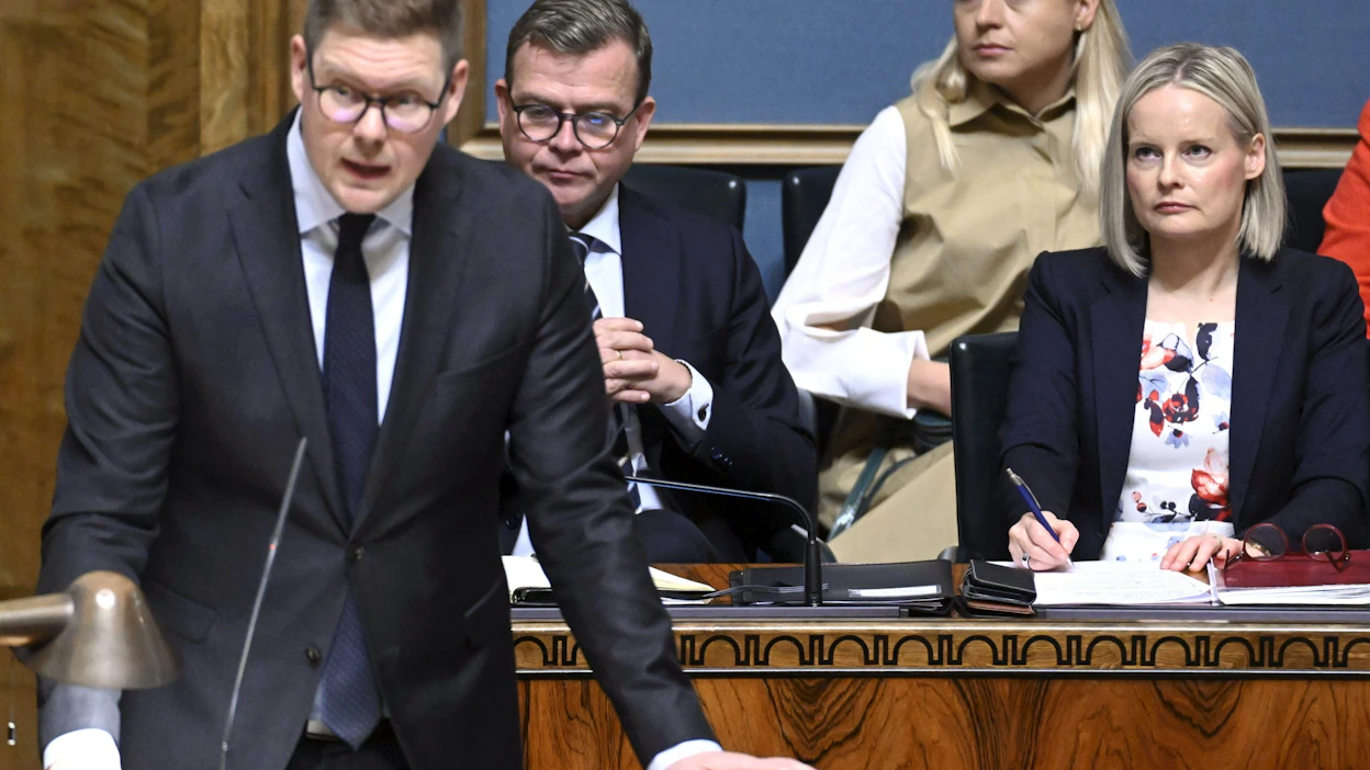SDP:n puheenjohtaja Antti Lindtman, pääministeri Petteri Orpo (kok.) ja valtiovarainministeri Riikka Purra (ps.) eduskunnan täysistunnossa 10. lokakuuta. Takarivissä ulkoministeri Elina Valtonen (kok.).