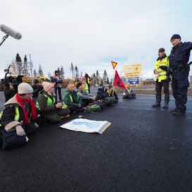 Elokapinan mielenosoittajat estävät liikenteen kulun Kemin Sahansaarentiellä. Tiellä on juliste, joka esittä Suomen metsien ikäjakaumaa.