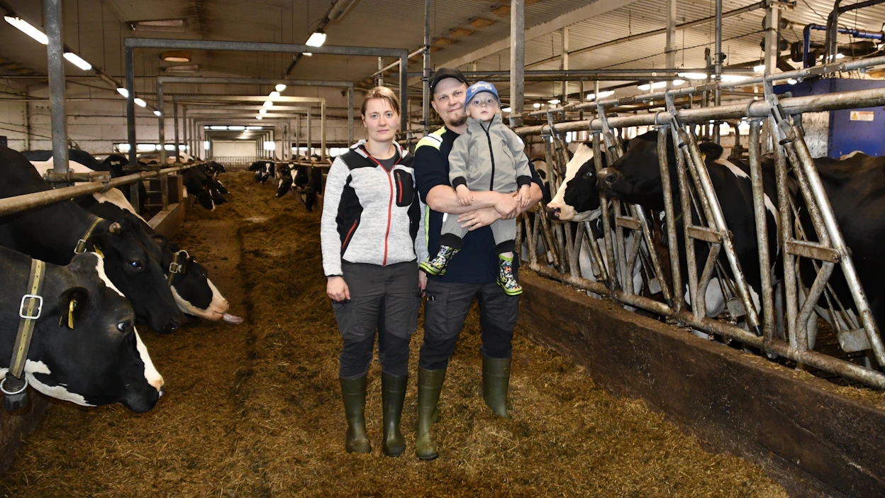 Veikka Heikura pyrkii optimoimaan työajan panostamalla navetan arkea helpottaviin ratkaisuihin. Kuvassa myös Annemari Jokela ja parin esikoinen Veikko.