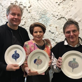 Pekka Paikkari (vas.), Margit Kojo ja Kati Tuominen-Niittylä esittelevät uusiolautasia, joihin on maalattu kasviksia.