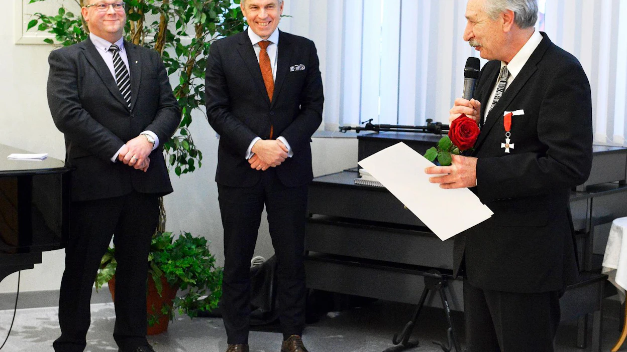 Jouni Jyrinki nauratti kiitospuheessaan kokousväkeä toteamalla, että näyttämöltä pitää poistua ja puhe lopettaa silloin, kun yleisö vielä taputtaa. Vasemmalla myhäilee MTK-Keski-Pohjanmaan johtokunnan varapuheenjohtaja Vesa Isolankila, jonka vieressä on MTK:n puheenjohtaja Juha Marttila. Marttila luovutti Jyringille Suomen Leijonan ritarikunnan ritarimerkin.