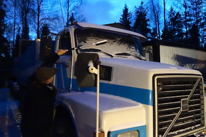Lumen harjaaminen työkoneen tai auton päältä tapahtuu yleensä aamutuimaan pimeässä. Riittävän pitkällä varrella varustettu työväline säästää tässä tilanteessa kiipeilyltä. Sinituotteen Kungs-sarjaan kuuluva teleskooppivartinen Tele-Is-lumiharja venyy 105 senttiin. Tämä maksoi Motonetissa 11,90 euroa. Harjan pituus riitti juuri ja juuri kuvan kuorma-auton lasien puhdistukseen. Varren toisessa päässä on kolmikulmainen vaihdettavalla terällä oleva jääraappa.