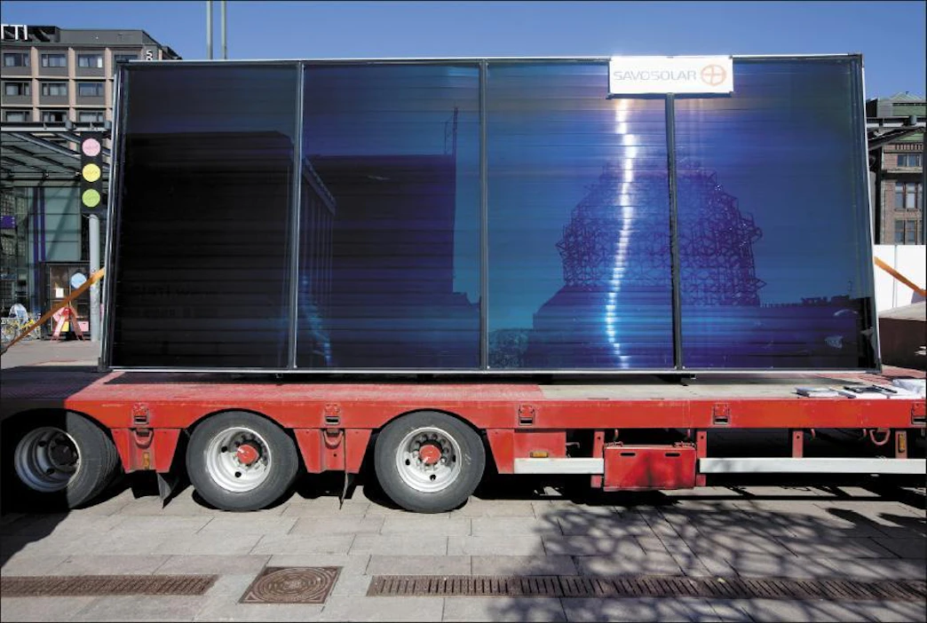 Aurinko ja Helsingin Narinkkatorin yrittäjäpatsas heijastuvat maailman suurimmasta aurinkokeräimestä. markku vuorikari