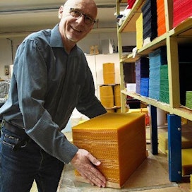 Pekka Paajanen valssaa värjättyä mehiläisvahaa levyiksi ja myy kynttilöiden tekijöille. Suosituimmat värit ovat valkoinen ja punainen.  KUva: Riitta Mustonen