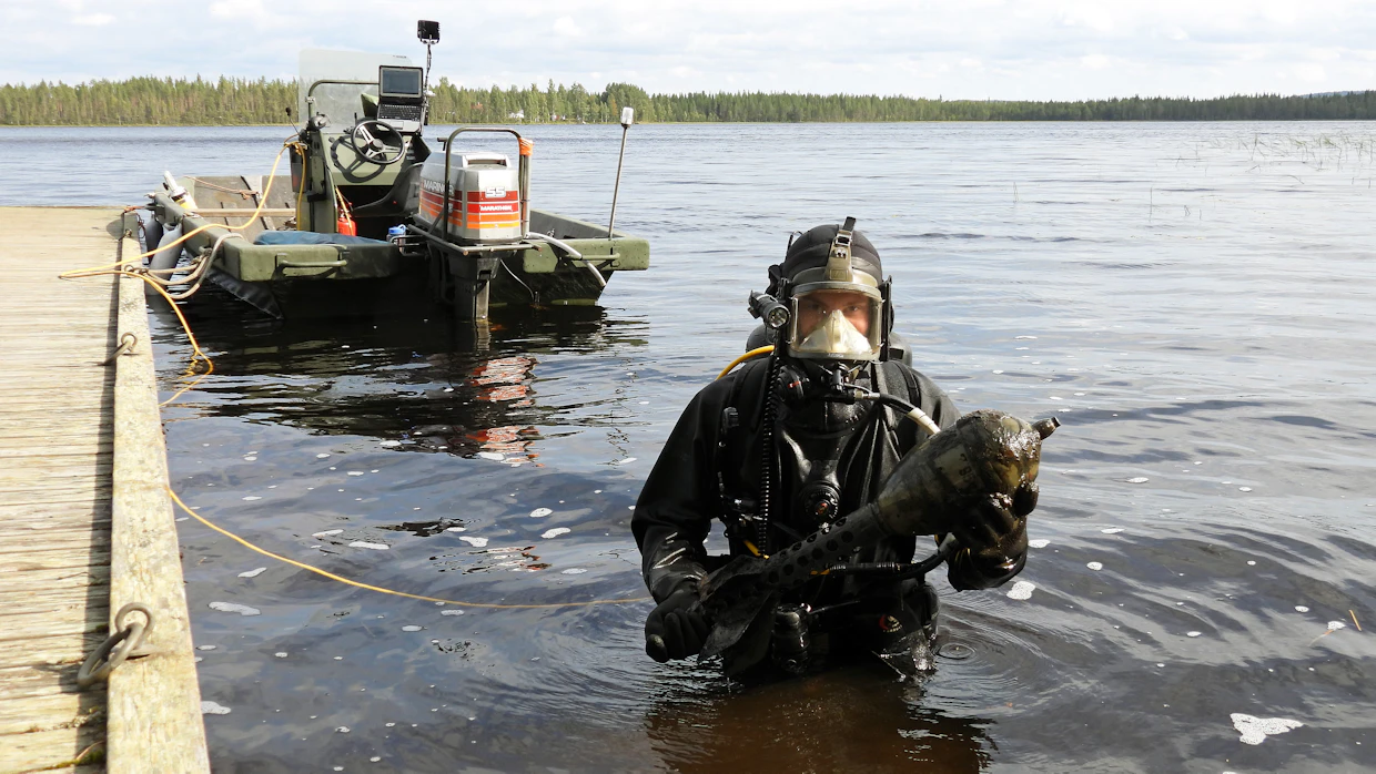 Jääkäriprikaatin sukeltaja nostaa saksalaisen panssaritorjuntatykin alikaliiperiammuksen Misin uimarannalta.