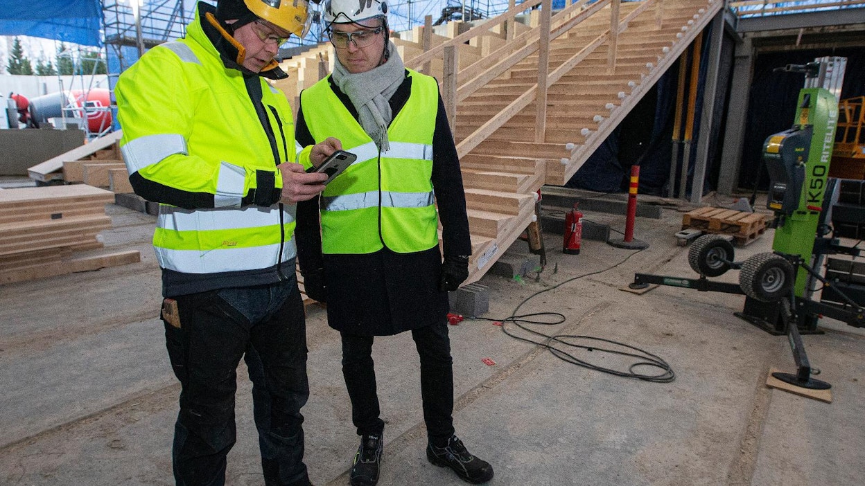 Kuninkaankylän Puurakentajien toimitusjohtaja Jyrki Huttunen ja Stora Enson Wood Products -divisioonan liiketoiminnan kehityspäällikkö Antto Kauhanen tutkivat älypuhelimesta Helsinkiin rakentuvan puukoulun työmaan etenemistä.