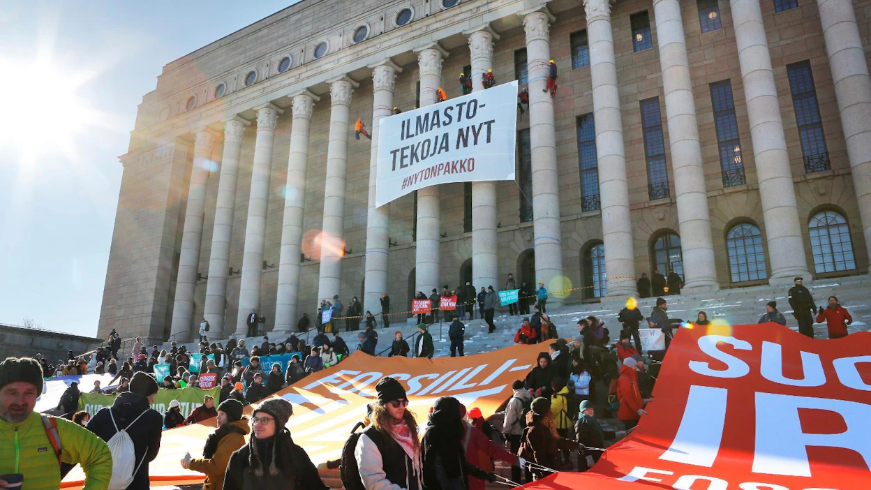 Greenpeacen aktiivit vaativat päättäjiltä ilmastotekoja 6.3. eduskuntatalolla. Järjestö ei ota rahaa vastaan julkisilta tahoilta ja yrityksiltä.