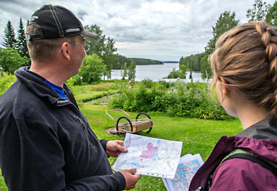 Lauri Kauppi tutkii metsässään karttaa, jossa riskialue on rajattuna.