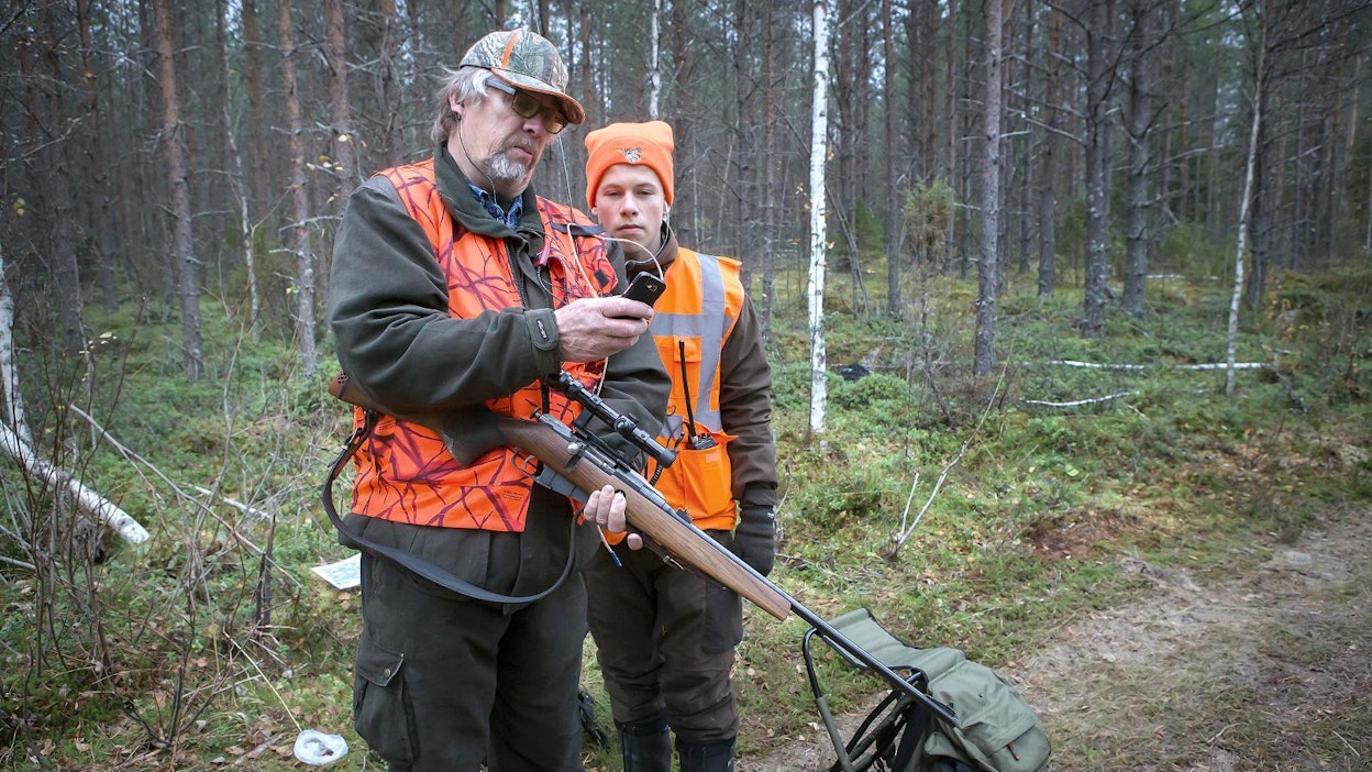 Osmo Virtanen ja kahdeksasluokkalainen Oskari Nissinen seuraavat passipaikalta, missä hirvikoira on liikkeellä.