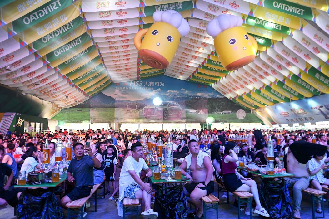 Kiinan Qingdaossa olutfestivaalilla ihmisiä nauttimassa juomia ja ruokaa. Kuvituskuva. AFP/Lehtikuva.