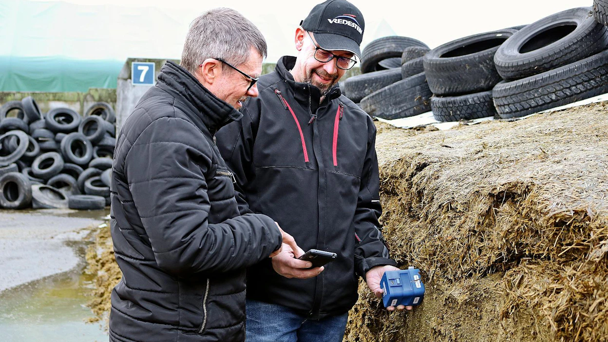 Projektipäällikkö Mikko Himanka, vas. ja pilottitilan isäntä Marko Sorvisto kokeilevat NIR-laitetta säilörehun leikattuun pintaan. Muutamassa sekunnissa laite kertoo, mitä on rehun kuiva-aineen ja raakavalkuaisen määrä.