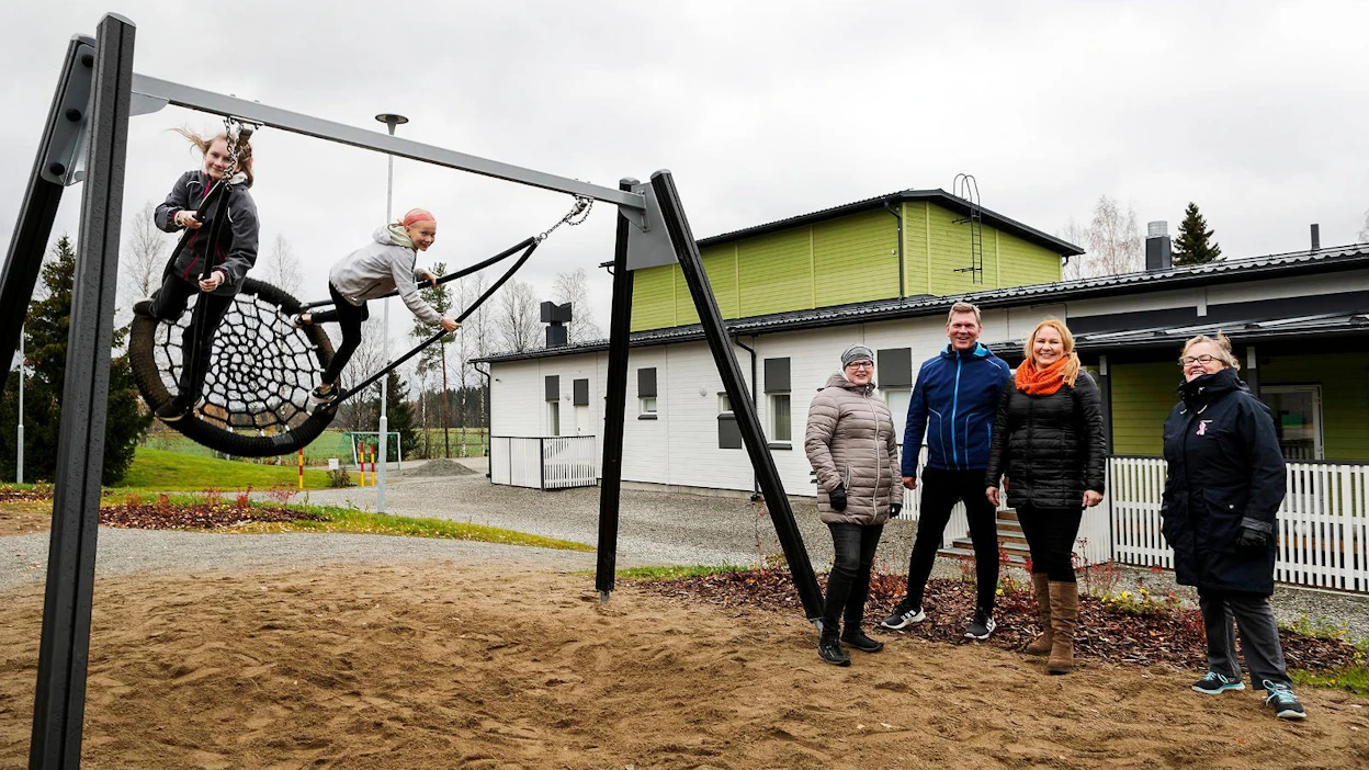 Vanhempainyhdistyksen puheenjohtaja Johanna Nousiainen (kuvassa vasemmalla), rehtori Jorma Patronen, koululaisen vanhempi Saara Kettunen ja kyläyhdistyksen sihteeri Helena Kumpulainen iloitsevat Runnin kylän uudesta koulusta ja toivovat sille pitkää ikää. Koulun oppilaat Iida Nousiainen ja Veera Kettunen kiihdyttivät keinun vinhaan vauhtiin.