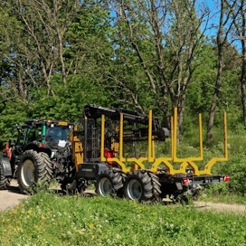 Kuvasta ei juuri näy, että traktorin ja metsäperävaunun yhdistelmä työskentelee Helsingissä. Kaupungin metsäosastolla on yli 4 000 hehtaaria hoidettavia puistoja ja metsäalueita. Useampi yhdistelmä hoitaa korjattujen puiden kuljetukset, uusimpana Kronoksen toimittama Kargo 121 -vaunuun perustuva yhdistelmä.