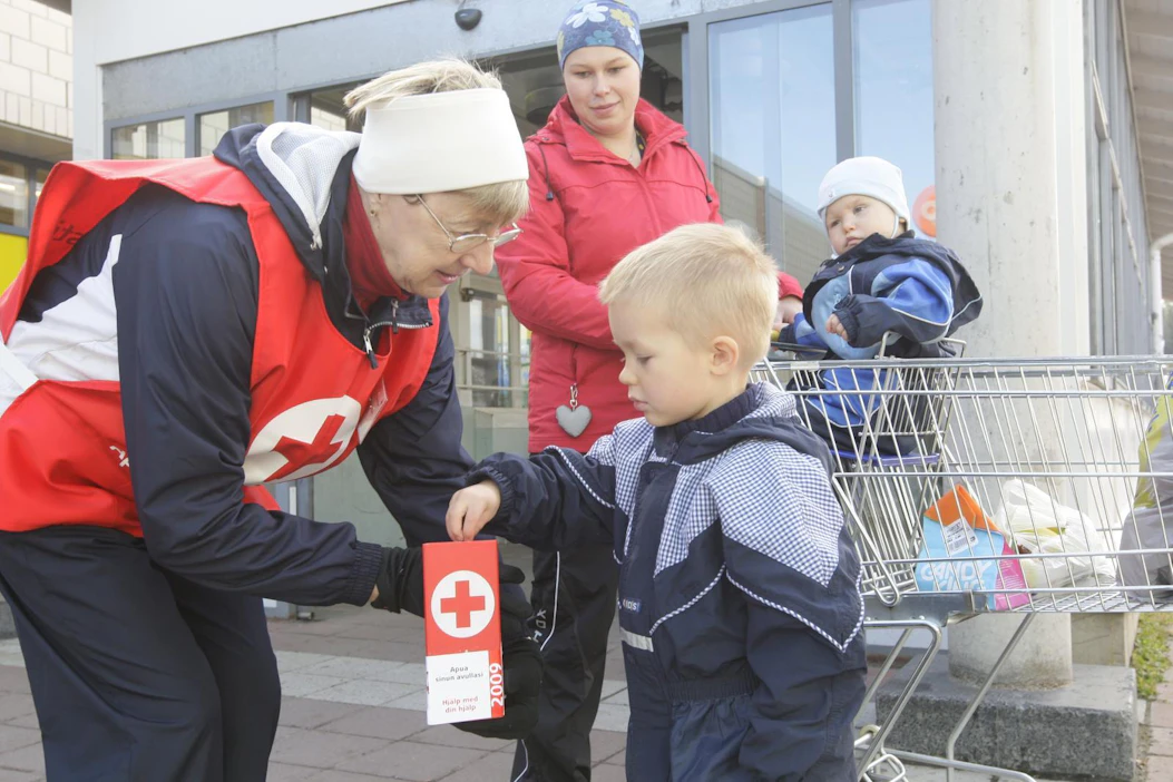 Kalle Savolainen pudotti oman lahjoituksensa Anna-Maija Niskasen Nälkäpäivä-lippaaseen Siilinjärven keskustassa vuonna 2009. Äiti Minna Savolainen ja pikkuveli Otto seuraavat.