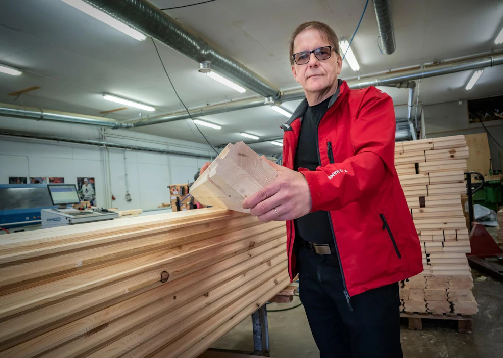 Toimitusjohtaja Pertti Vainiola esittelee järeän luokan liimahirttä, josta tyypillisen mökin runko voidaan Teuvan Mökki- ja Sorvituotteella rakentaa.