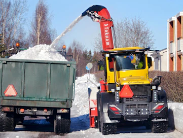 Kevyen liikenteen väylä on täynnä lunta ja lingon työleveys on käytössä. Lumisuihku on tiivis ja sitä saadaan liikkeelle lavalle reilu neljä kuutiota minuutissa.