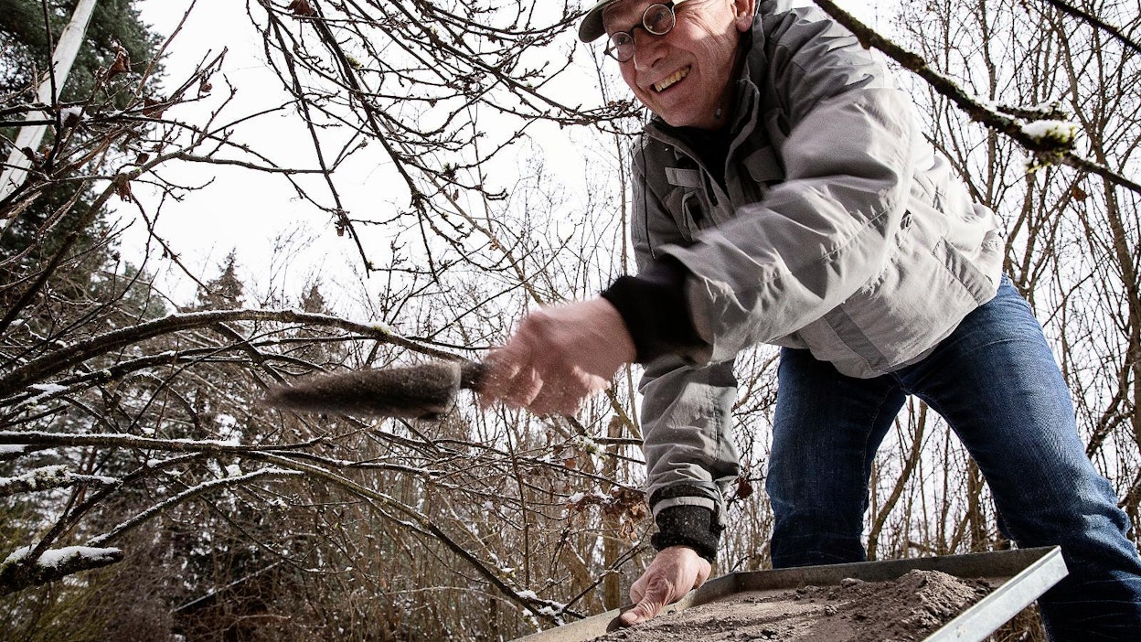 Nurmijärveläinen Matti Turpeinen levittää omakotitalonsa takan tuhkat puutarhaan marjapensaiden ja omenapuiden juureen.
