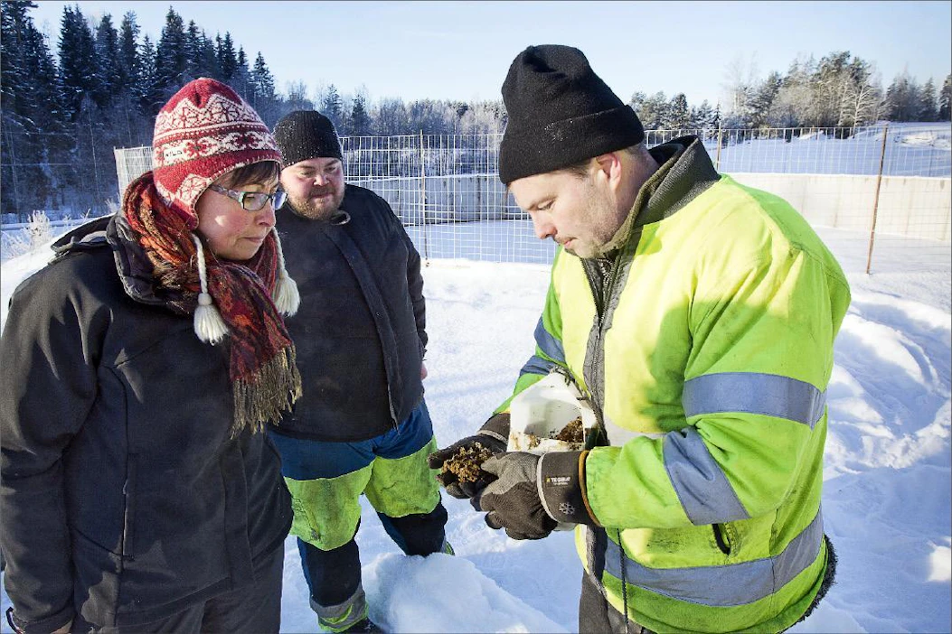 Tero Savela (oik.) esittelee lietteestä erotettua kuiva-ainetta Kaisa Riikolle. Taustalla Janne Kinnunen. Kari Salonen
