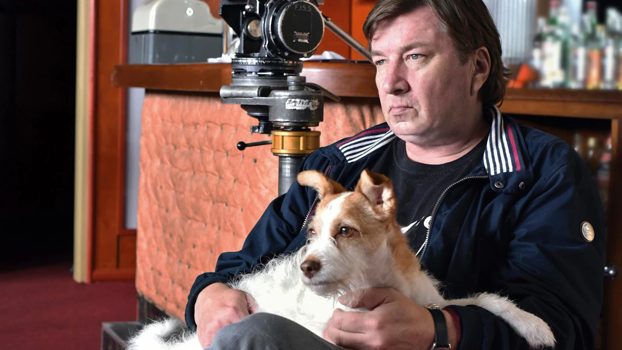 Aki Kaurismäki Toivon tuolla puolen -elokuvan kuvauksissa Varpu-koiran kanssa.