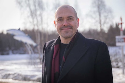 Mies pikkutakissa hymyilee.