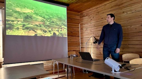 Mies pitää powerpoint-esitystä Karigasniemen kylätalolla. Tutkija Panu Orell. 