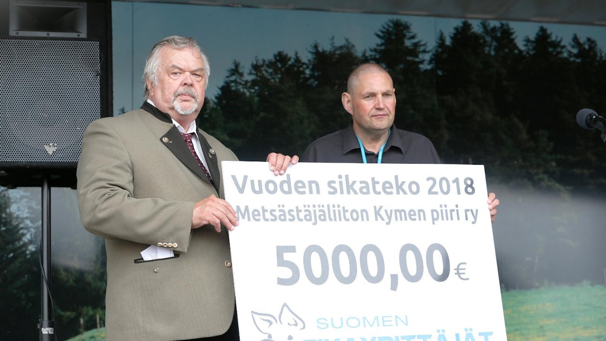 Suomen metsästäjäliiton Kymen piirin toiminnanjohtaja Erkki Pentinniemi (vas.) vastaanotti vuoden 2018 Sikateko-palkinnon keskiviikkona Okra-näyttelyssä. Palkinnon luovutti Martin Ylikännö.