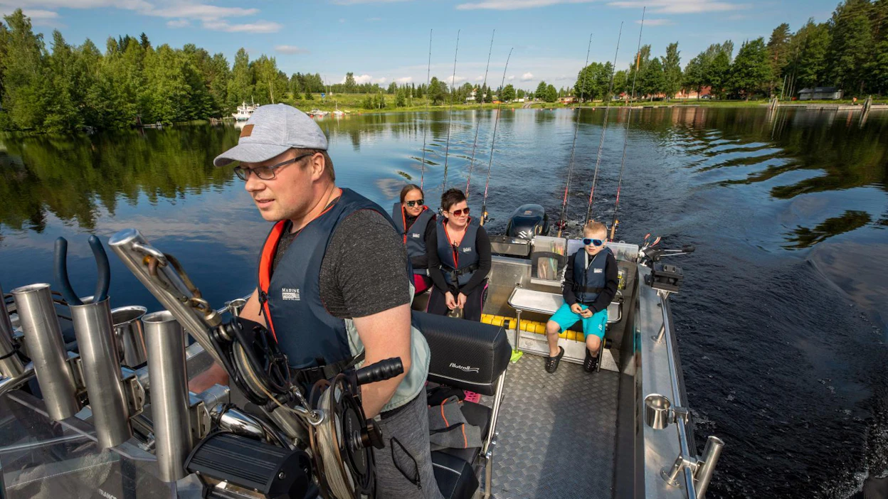 Kalastusopas, matkailuyrittäjä Janne Parviainen opastaa turisteja kalastamaan kymmeninä päivinä vuodessa. Taustalla Elisa Tarkiainen, sekä Armi ja Jimi Parviainen kalastusreissulla tiistaina Unnukalla Leppävirralla.