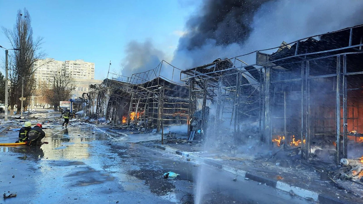 Ukrainan valtiollisen pelastusviranomaisen keskiviikkona välittämässä kuvassa pelastajat sammuttavat ohjusiskujen sytyttämää paloa torilla Harkovassa. LEHTIKUVA / AFP