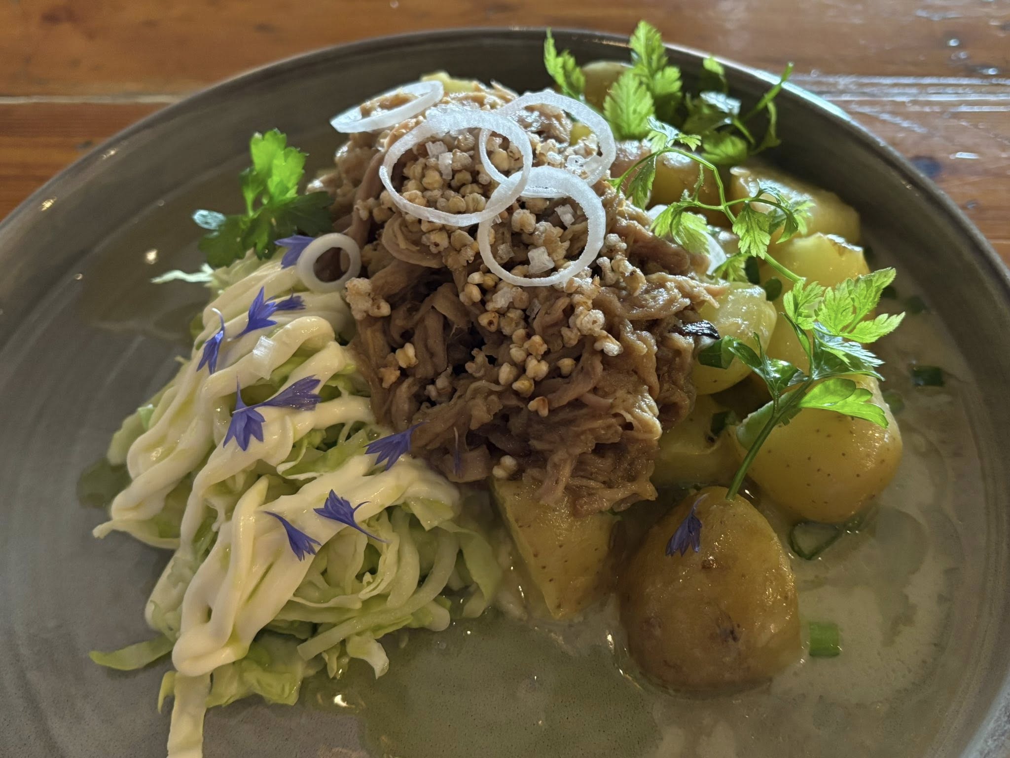 Nyhtöpossun päällä näkyy tattaria ja fenkolia. Annos on koristeltu ruiskukin.