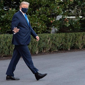 Presidentti Trump käveli Valkoiselta talolta helikopterille avustamatta ja maski kasvoillaan. LEHTIKUVA / AFP