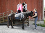 Emma Kalliola ja Sanna Pohjolainen (takana vas.) avustavat Hanna Tapolan rampilta hevosen satulaan. Islanninhevosta Naskur fra Sahalaa ohjaa Raija Valkonen.