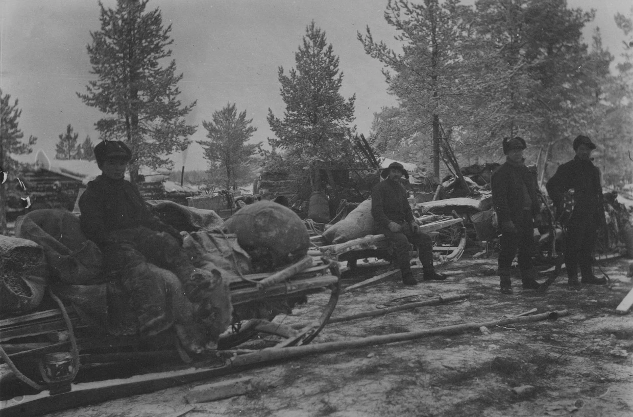 Miehiä ja poikia kämpän edustalla Lapissa 1920- tai 1930-luvulla otetussa kuvassa. Työvälineinä olivat kirveet, hevoset ja tukkireet.