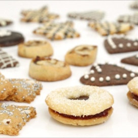 Samasta perustaikinasta syntyy tähtitaivasneliöitä (edessä vasemmalla), herrasväenleipiä (etuoikealla), keskellä taatelikierteet ja suklaasydämet, takana suklaalla koristeltuja pikkuleipiä. Jaana Kankaanpää