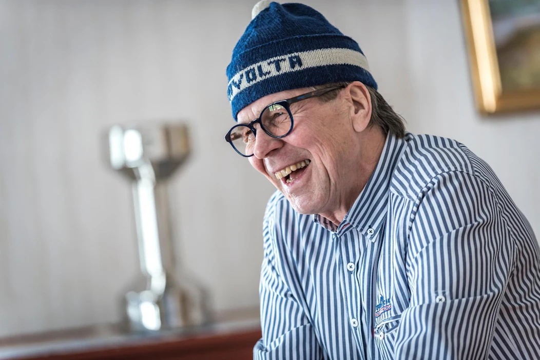 "Kaikki tuntevat minut Travolta-nimellä", Antero Nuuttila nauraa kotonaan nimikkopipo päässään. Taustalla näkyy hänen mäkihypyn eteen tekemästään elämäntyöstä ojennettu Uno-pokaali.