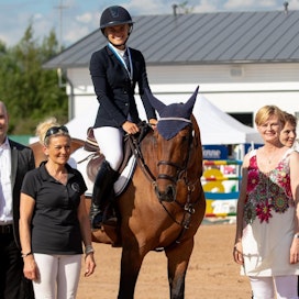 Kuvassa Jukka Koivisto kesän esteratsastuksen SM-kilpailussa palkitsemassa Emma Tallbergia ja Arvenia.