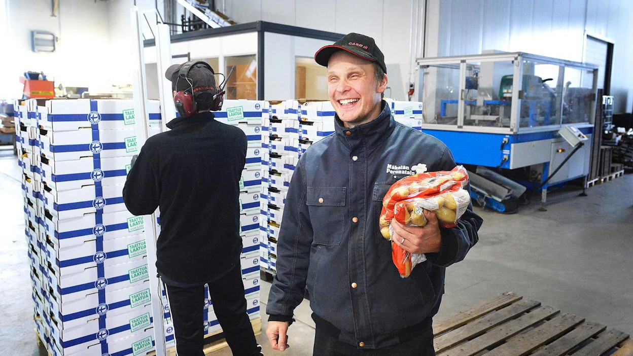 Mäkelän perunatalo pakkaa perunaa pääasiassa kahden kilon pusseihin, joita Kimmo Mäkelällä on sylissä. Taustalla Teemu Niemi pakkaa Lidlille lähteviä laatikoita.