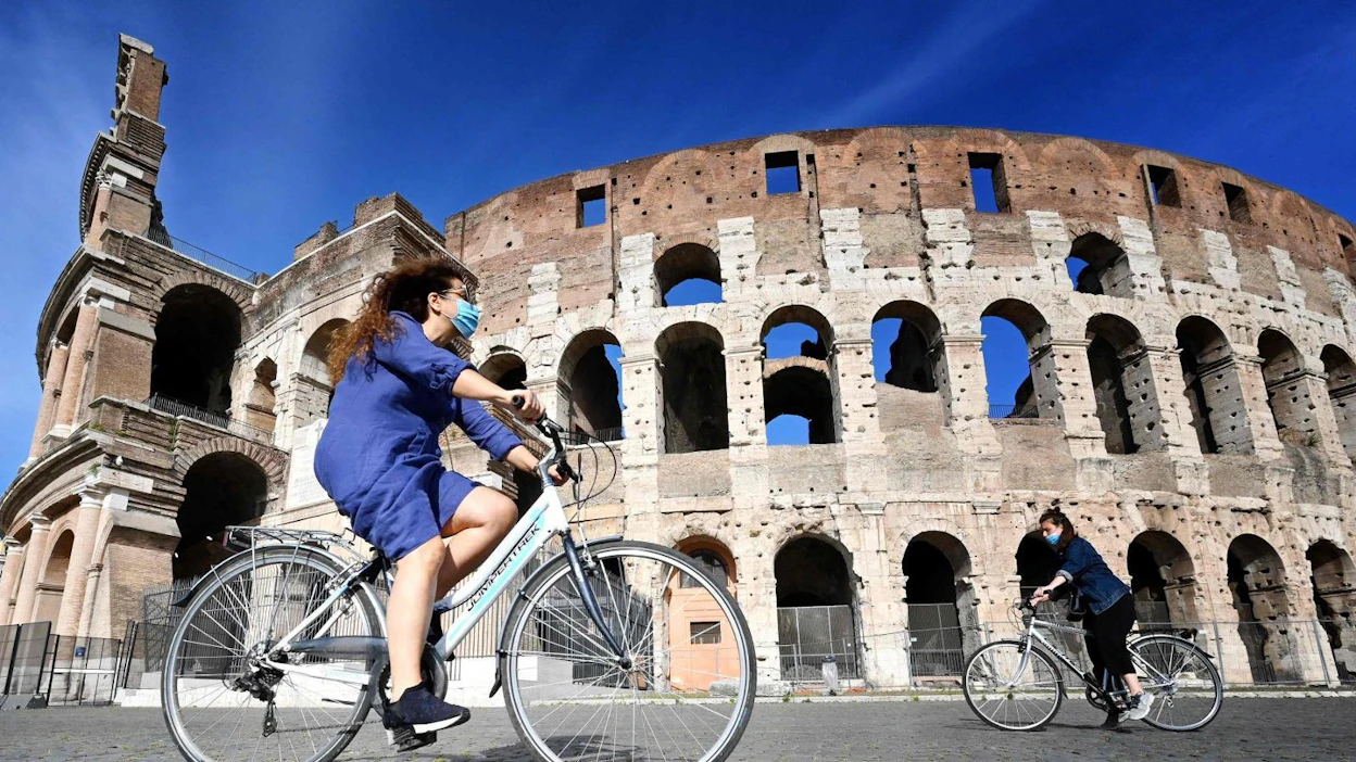 Italia on höllentämässä koronarajoituksia. Pyöräilijät ohittamassa Rooman kuuluisaa Colosseumia 8. toukokuuta.