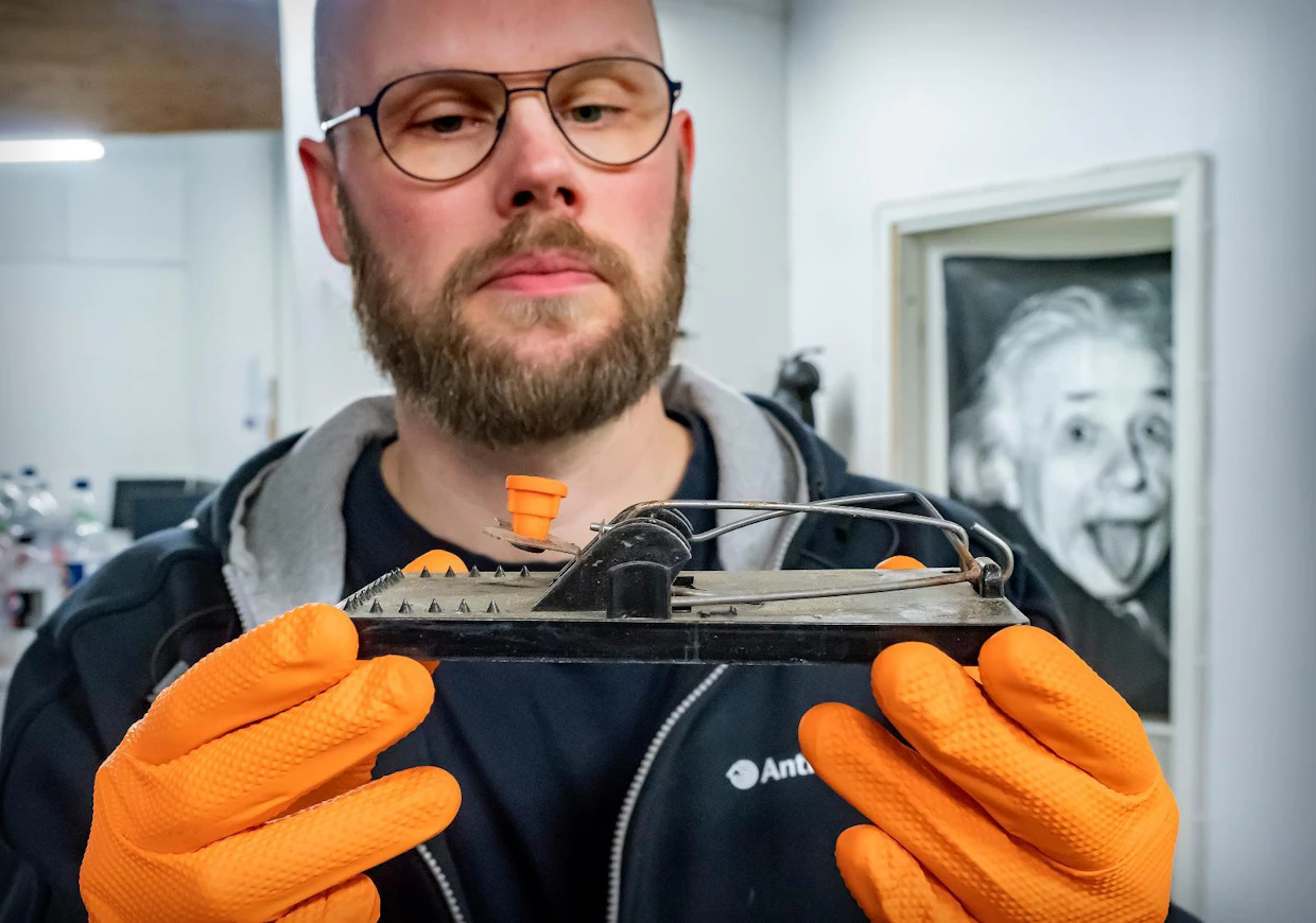 Jukka Tietäväinen pitelee vanhan mallin rotanloukkua, johon on asetettu houkutin.