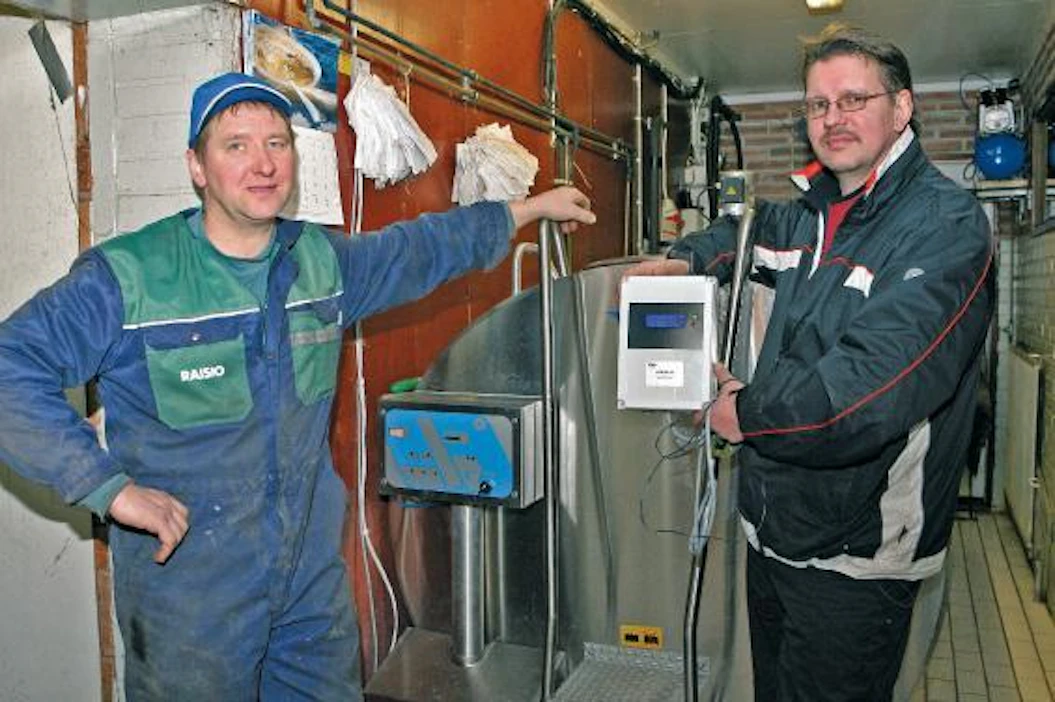 Kuusisto-Laakso ja keskusyksikkö samaa kokonaisuutta: "Timo (vas) ja Soili Kuusiston tilalla a-Milk on ollut käytössä kohta vuoden päivät. Erkki Laakson (Ertela Oy, oik) kädessä tuore esittelymalli, jossa on mukana myös reaaliaikanäyttö. Näytöltä on heti nähtävissä, että kaikki on kunnossa. Lisäksi vihreä valo ilmoittaa, että mitään häiriöitä ei ole esiintynyt sitten edellisen noutokerran. Punainen valo ilmoittaisi, jos jaksolla on ollut jokin normaalista poikkeava tilanne. Tällöin voidaan tarkistaa, mikä on ollut poikkeaman syy.