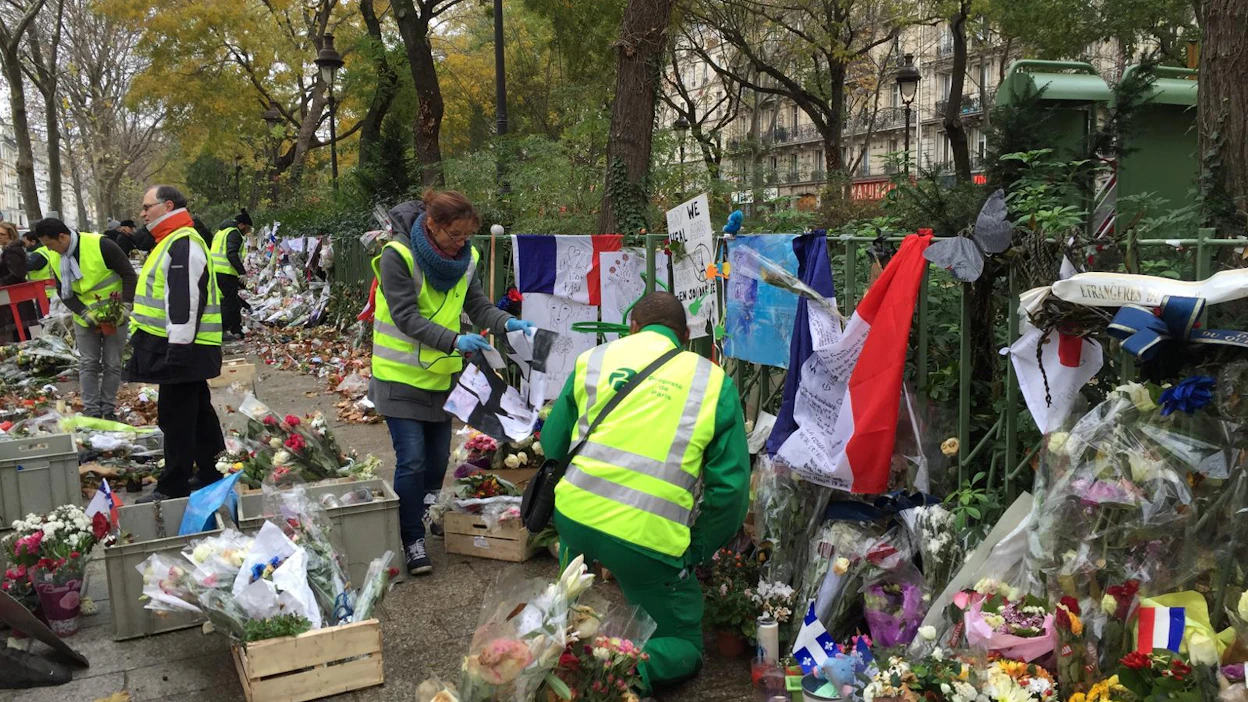 Pariisin puisto-osaston työntekijät siivoavat pois muistoesineisiin, kukkakimppuihin ja kirjeisiin tarttuneita lehtiä. Kaikki mikä pystytään säästämään, siirretään Bataclan-teatteria vastapäätä seisovan aidan juurelle. Nuolta näpäyttämällä pääset kastomaan lisää kuvia.