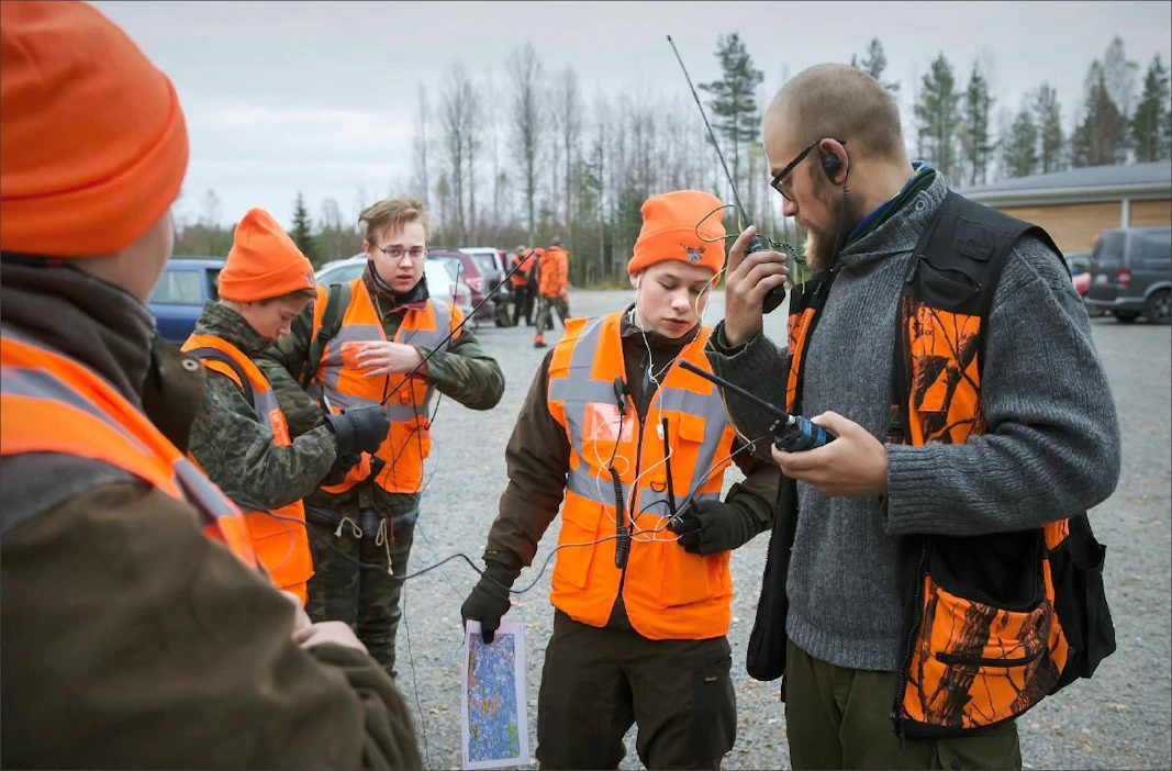Opettaja Jarno Simpanen (oik.) auttaa Oskari Nissiselle radio-puhelimen kuntoon, jotta viesti-liikenne pelaa passipaikalla. Aleksi Noponen ja Tommi Pölkki ovat valmiita aloittamaan jahdin. Johannes Tervo