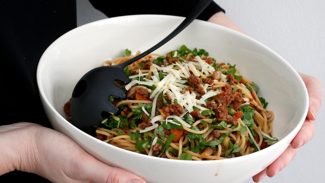 Pasta bolognese soijakastikkeella viimeistellään juustoraasteella ja tuoreyrtillä.