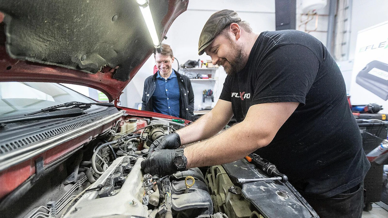 Serko Nieminen (oik.) asentaa Eflexfuel-etanolimuunnossarjaa bensiini-Toyotaan Pirkkalan asennuspisteellä ja Etanoliautoilijoiden toiminnanjohtaja Vilhartti Hanhilahti seuraa tarkasti.