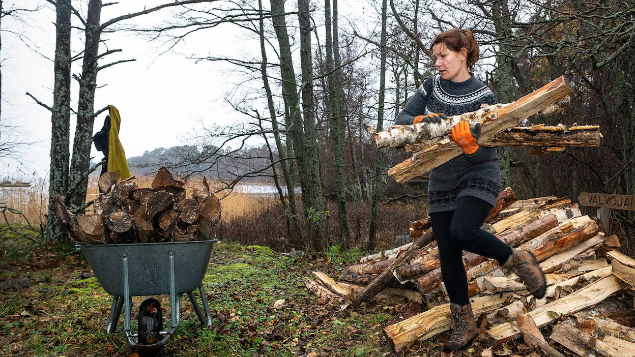 Opas Satu Haanpää-Heikkilä kantaa polttopuita ja löytää maastosta oluttölkin. ”Sitä aina ihmettelen, että porukka jaksaa tuoda tänne täysiä tölkkejä ja kävellä ne käsissä ympäriinsä. Mutta tyhjiä niitä jemmataan vaikka minne, vaikka ne olisi yhtä helppo viedä sillä omalla veneellä poiskin.”