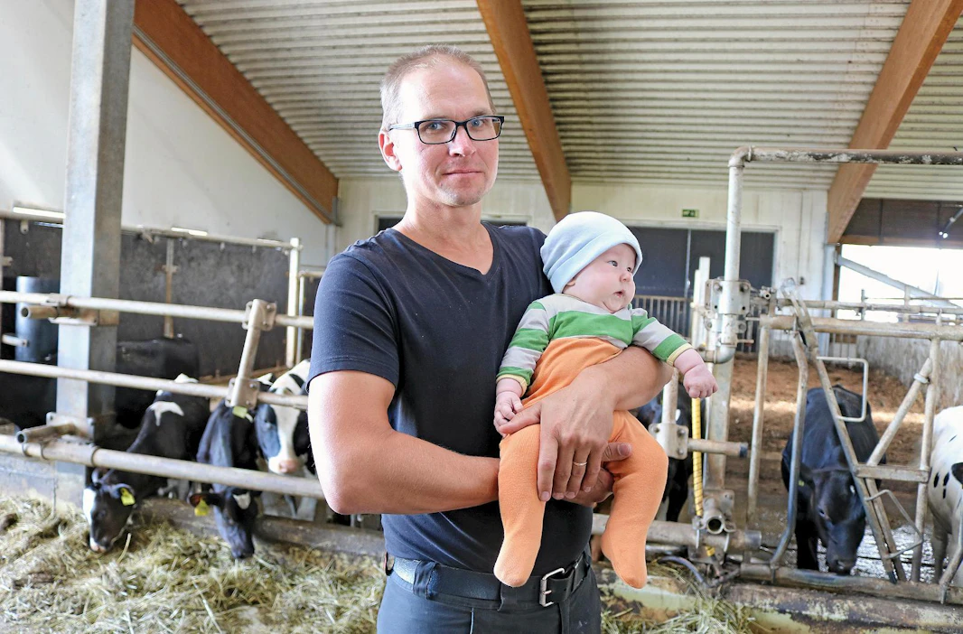 Neljän kuukauden ikäistä Jeremiasta sylissään pitelevä Antti Tuukkanen iloitsee tulevasta navetan laajennusprojektista. "Toisen robotin myötä myös karjamäärä tuplaantuu ja samalla voimme muutenkin tehostaa maidontuotantoa."