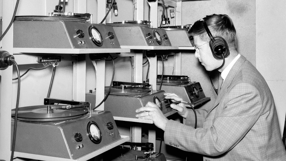 Kuvassa Suomen tietotoimiston toimitus vuonna 1962. Radiouutistoimituksen Kaj Linden lukee puheliuutisia levylle.