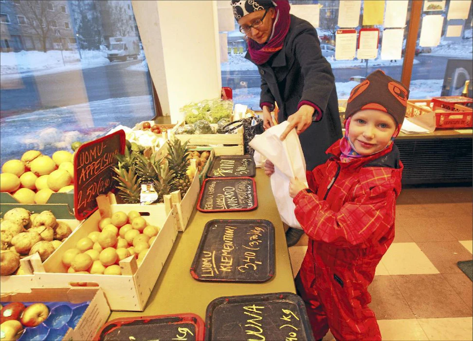 Herttoniemen ruokapiirin jäsen Niina Lappalainen nouti perjantaina tilaamansa tavarat Herttoniemen asukastilasta. Teo-poika avusti tomaattien punnituksessa. Kari Salonen