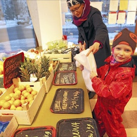 Herttoniemen ruokapiirin jäsen Niina Lappalainen nouti perjantaina tilaamansa tavarat Herttoniemen asukastilasta. Teo-poika avusti tomaattien punnituksessa. Kari Salonen