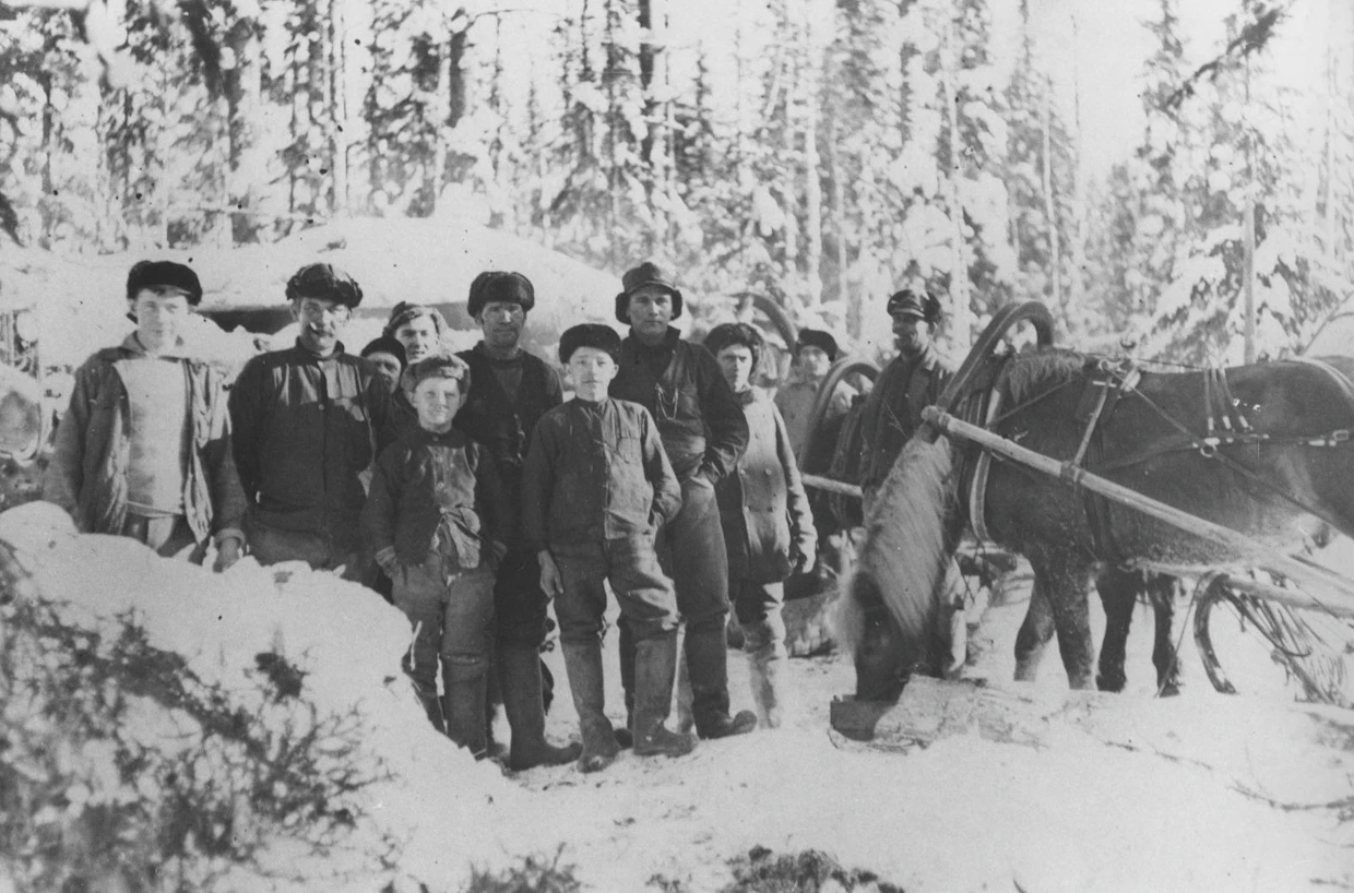 Savottalaisia turkislakeissaan kämpän edustalla 1920–1930-luvulla, mukana myös hyvin nuoria poikia. Kuva on Ilomantsista.