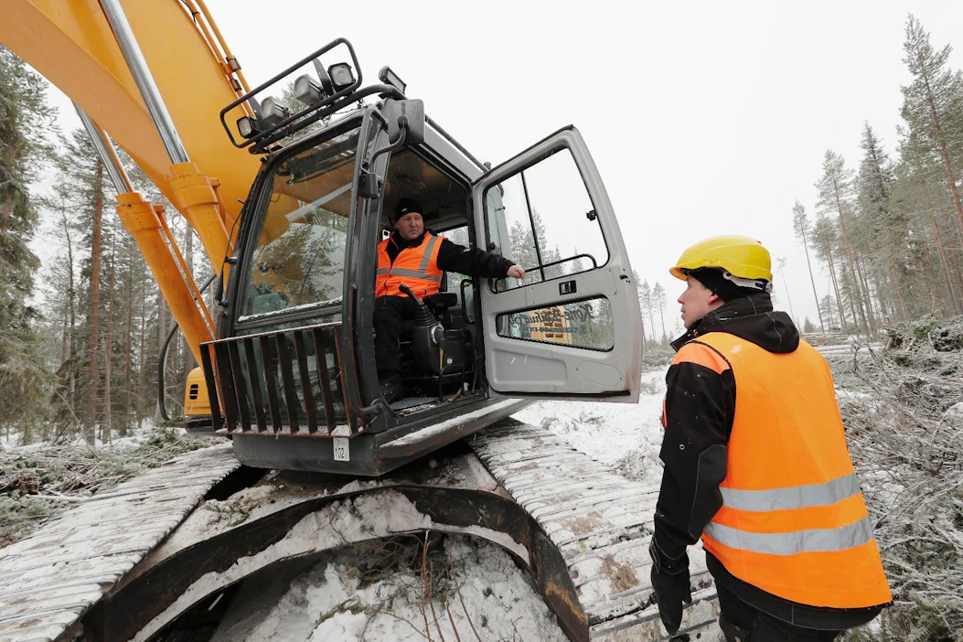 Kaivinkonetta kuljettava Veijo Kaihua keskustelee poikansa, toimitusjohtaja Janne Kaihuan kanssa päivän töistä.